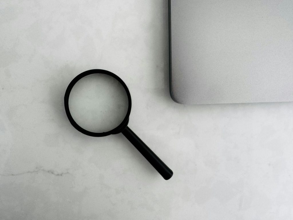 Magnifying glass beside a laptop, representing SEO and search visibility
